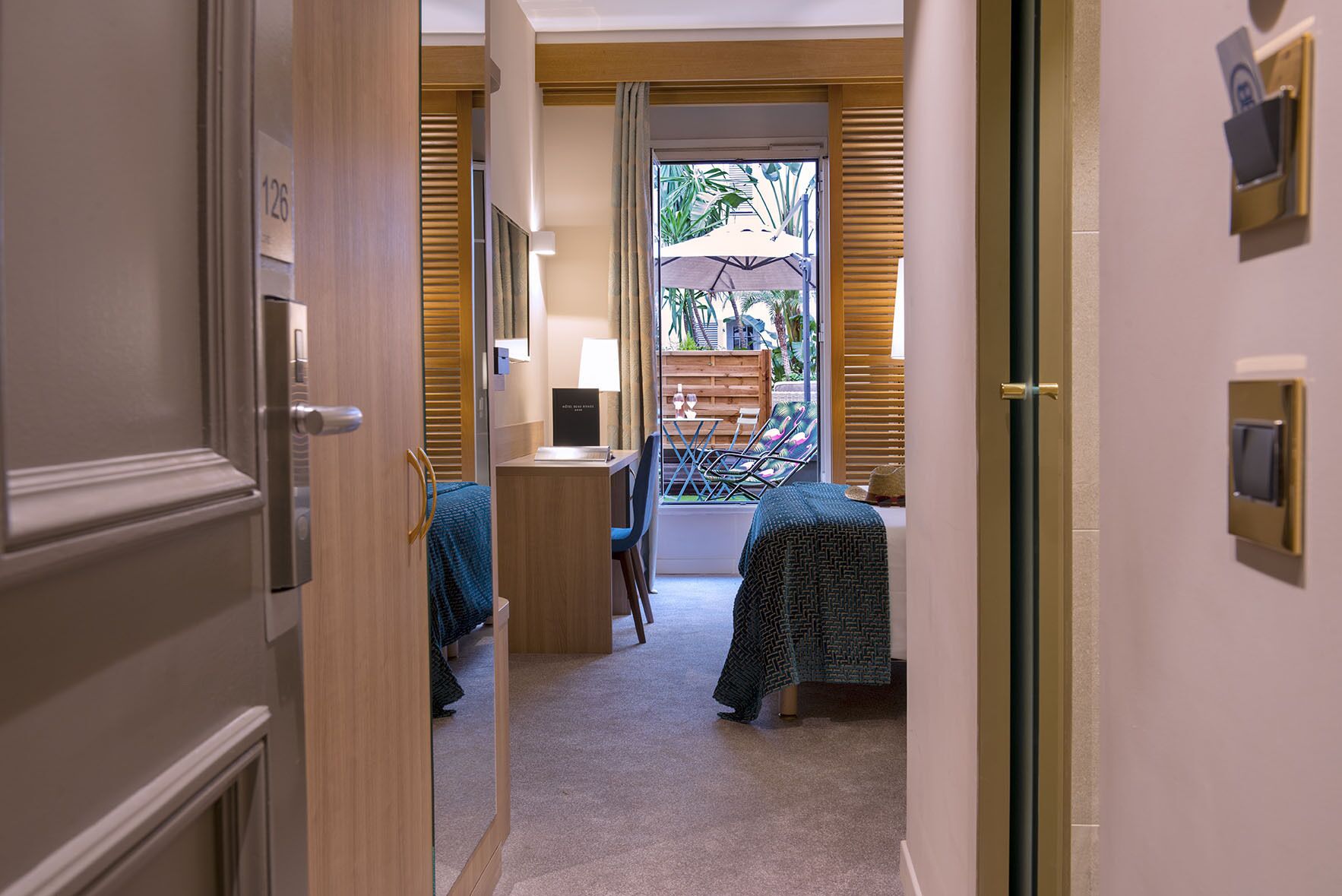 Ein Hotelzimmer mit Bett, Schreibtisch, Stuhl und einem Fenster mit Jalousien.