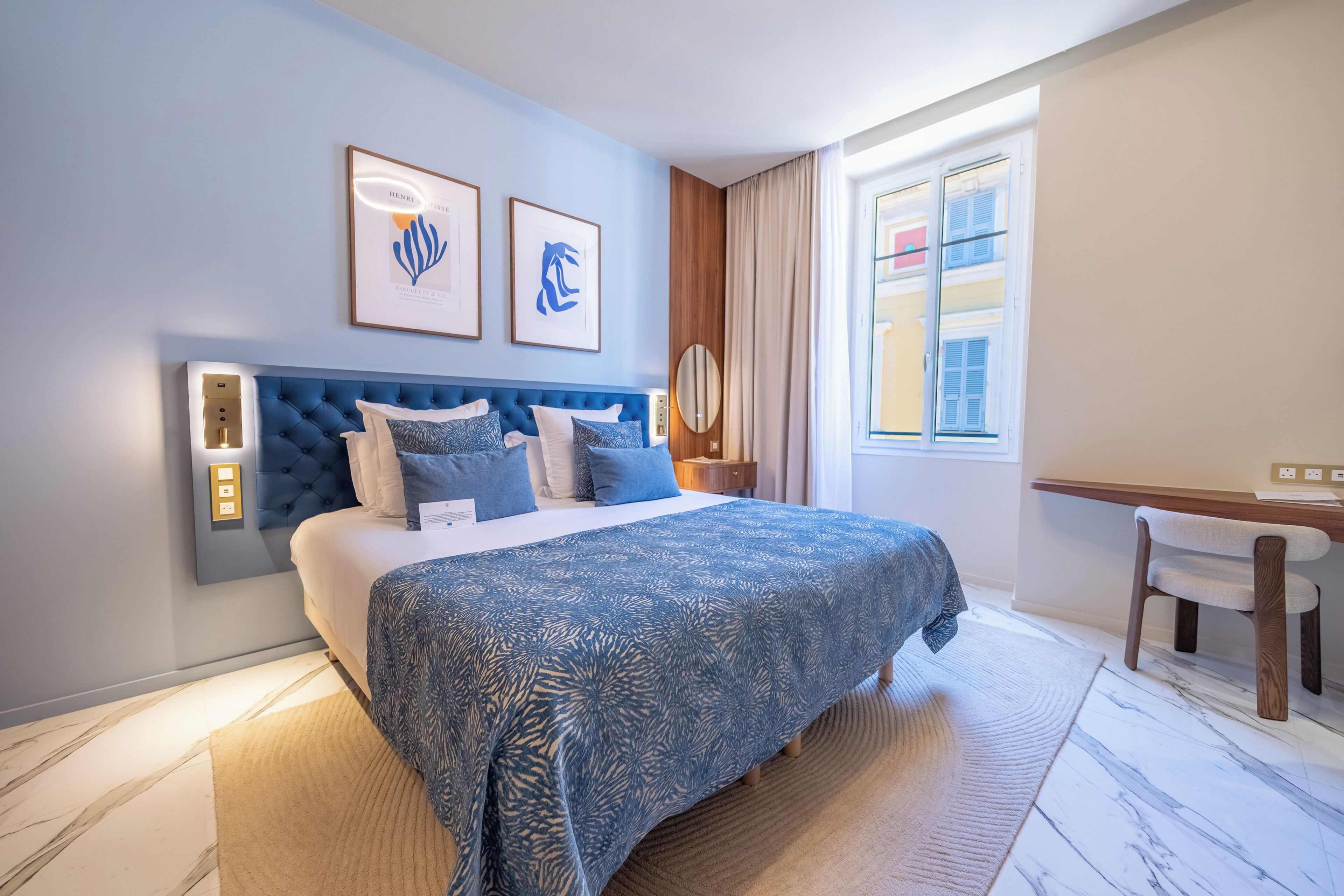 Ein Hotelzimmer mit einem großen Bett, einem Schreibtisch und einem Vorhangfenster.