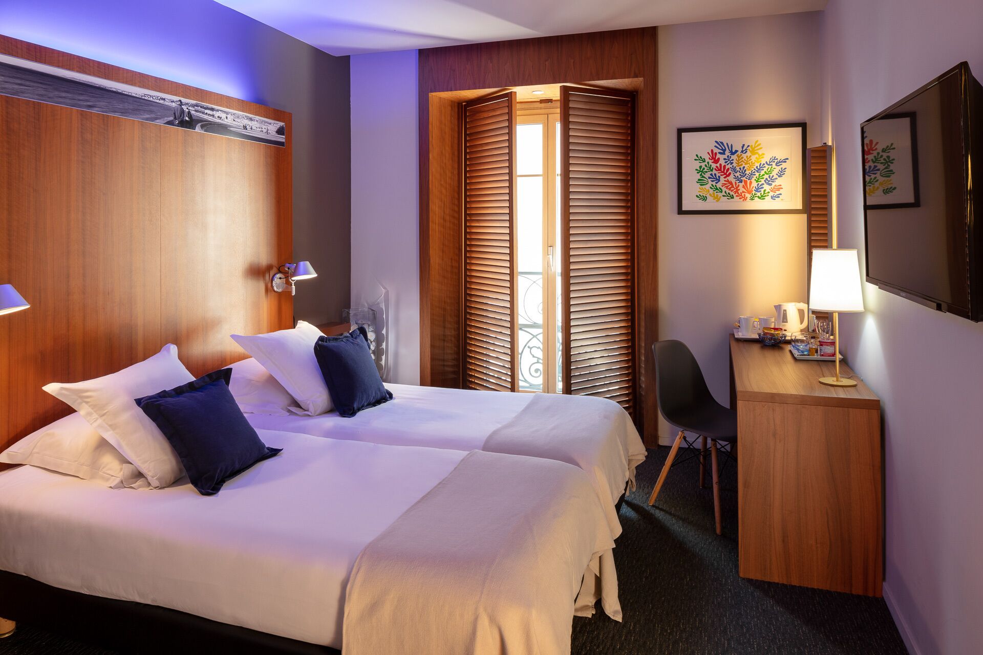 A hotel room with two beds, a desk, and a chair.