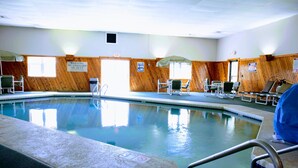 Une piscine intérieure avec des murs en bois, un poste de surveillance pour les sauveteurs et des espaces pour s’asseoir.