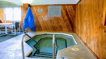 A whirlpool with wooden walls and a sign detailing use rules.