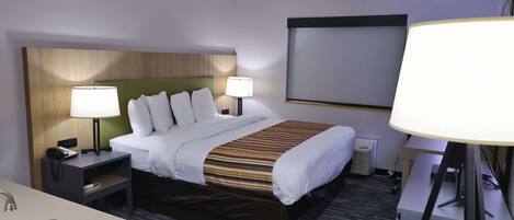 Een hotelkamer met een bed, twee nachtkastjes met lampen, een bureau, een stoel en een groot raam.