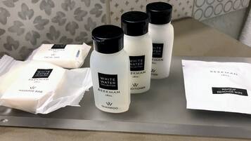 A tray with various skincare products including a massage bar, shampoo, conditioner, and makeup remover wipe.