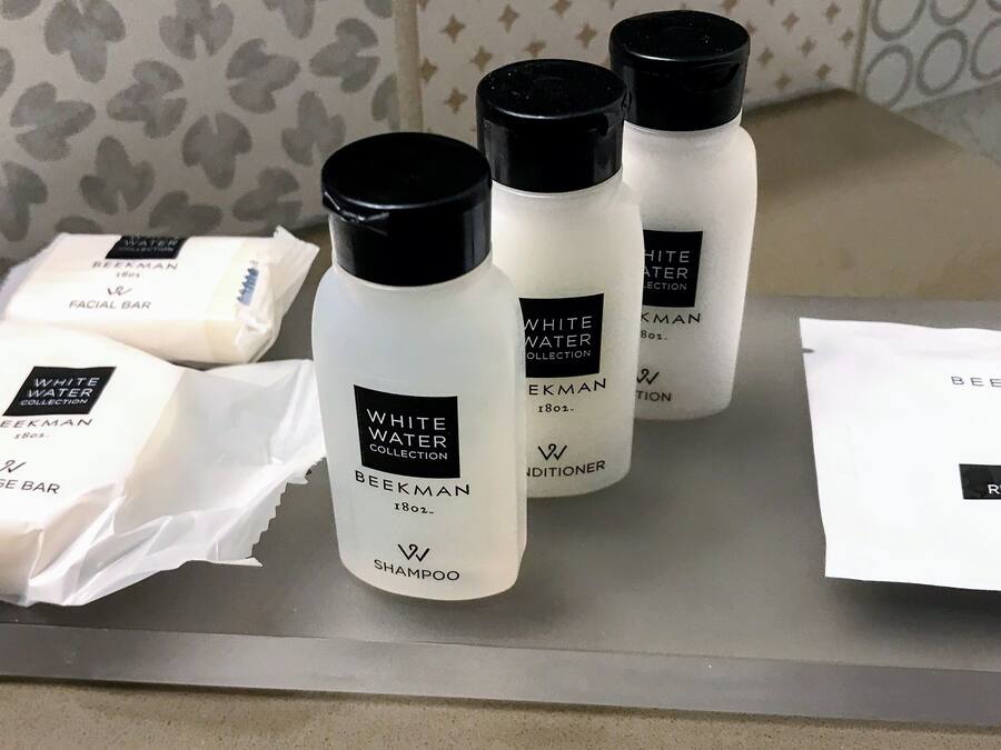 A tray with various skincare products including a massage bar, shampoo, conditioner, and makeup remover wipe.