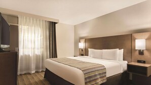 A hotel room with a large bed, a bedside table, a TV, and a window with curtains. - Country Inn & Suites by Radisson, Fergus Falls, MN (Fergus Falls)