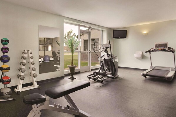 A gym with cardio equipment, weight machines, and dumbbells.