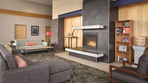 A modern living room with a fireplace, a sofa, a coffee table, and a bookshelf. - Country Inn & Suites by Radisson, Fergus Falls, MN (Fergus Falls)