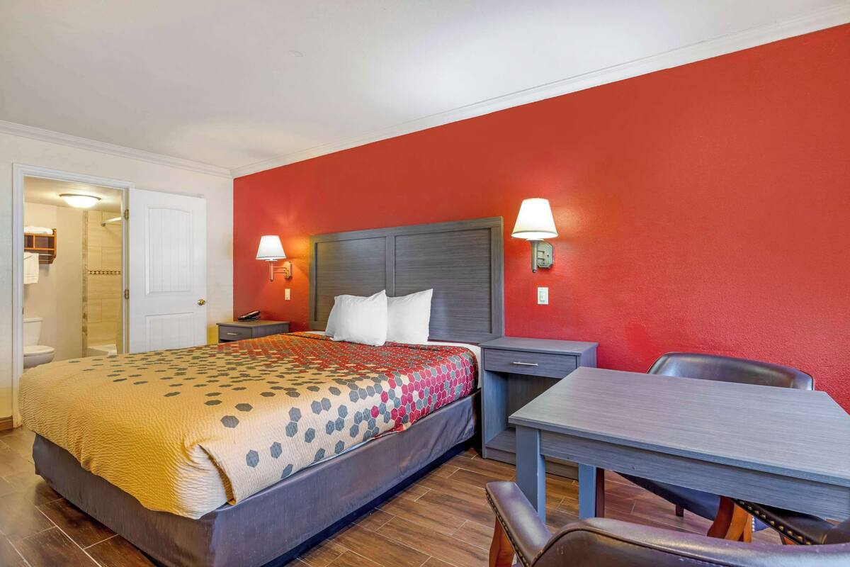 A hotel room with a bed, bedside tables, a desk, and a chair.