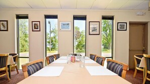 Une salle de conférence avec une longue table, des chaises et des tableaux encadrés accrochés aux murs.