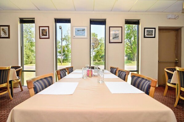 A conference room with a long table, chairs, and framed pictures on the walls.