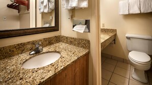 Une salle de bain avec un lavabo en granit, un miroir, des toilettes et un porte-serviettes avec des serviettes.