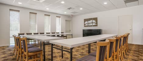 A conference room with a long table, chairs, a television, and a patterned carpet.