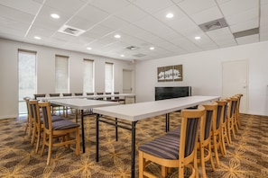 A conference room with a long table, chairs, a television, and a patterned carpet.