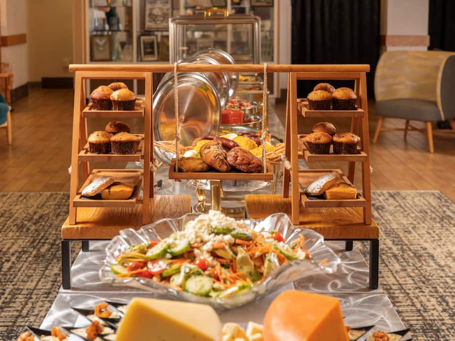 Disposición de buffet con diferentes tipos de comida y una ensalada al frente.