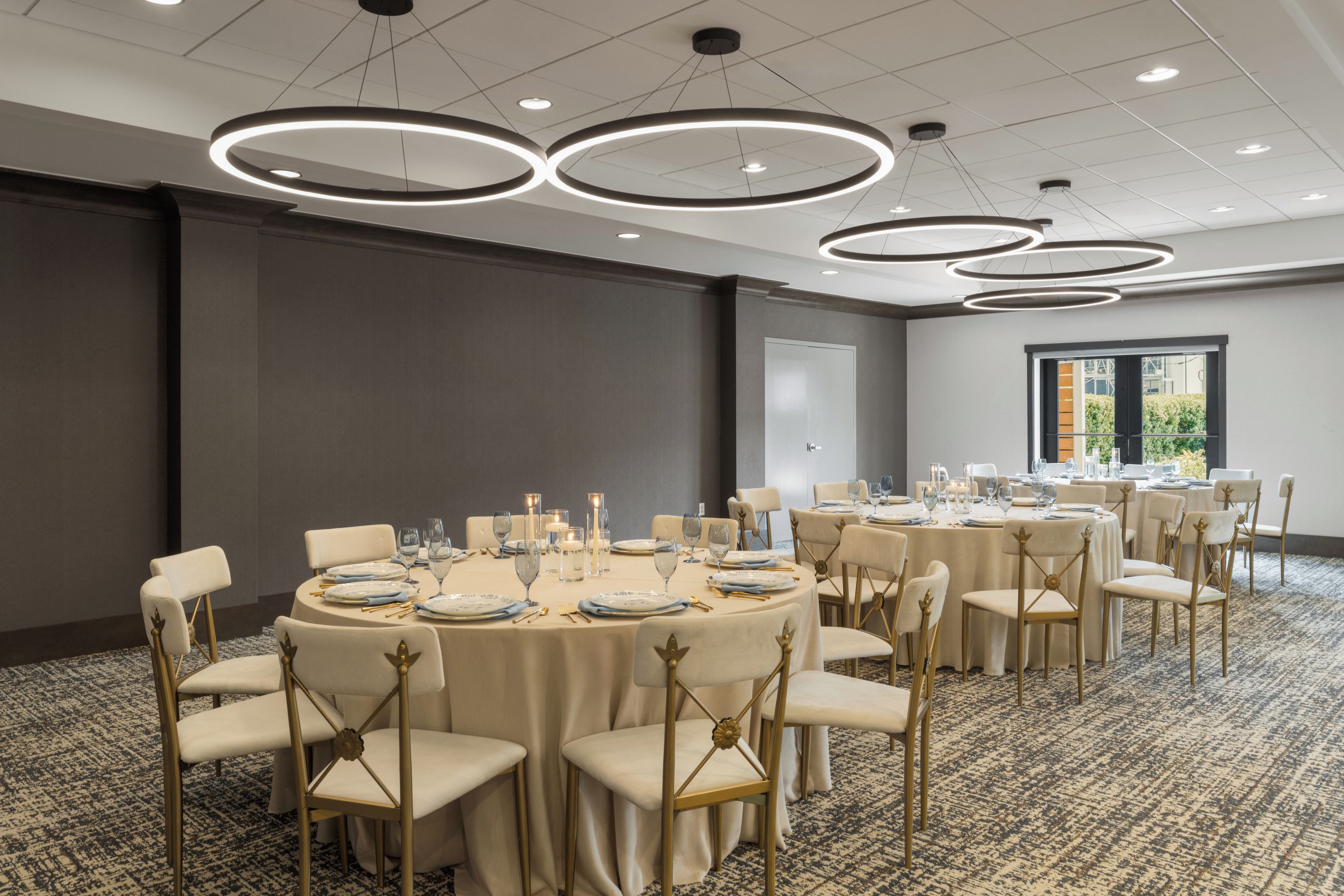 Un salón de conferencias con mesas redondas, sillas e iluminación colgante.