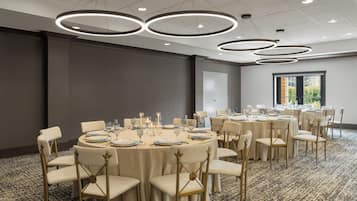 Un salón de conferencias con mesas redondas, sillas e iluminación colgante.
