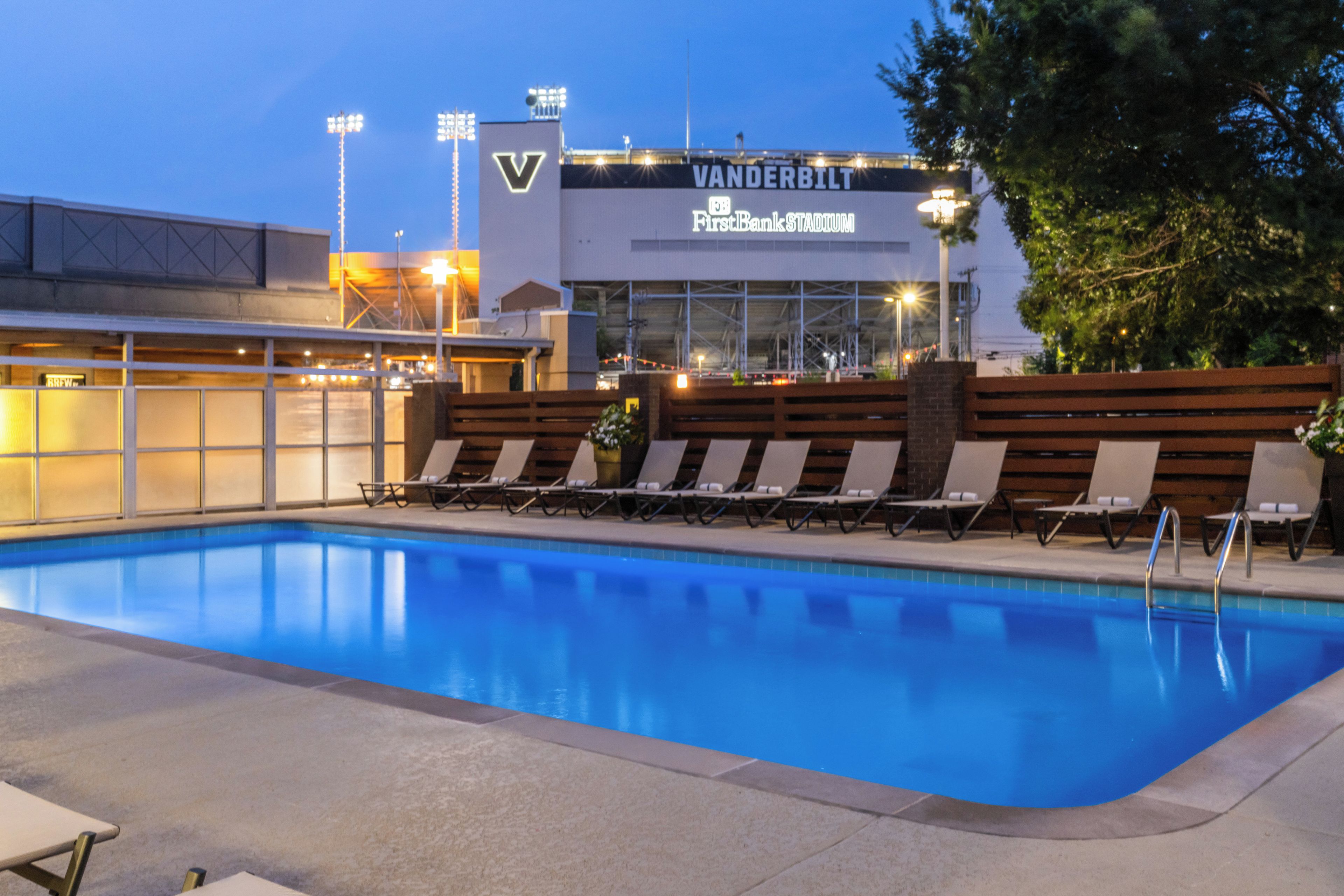 A swimming pool with lounge chairs and a building with 'VANDERBILT' signage in the background.