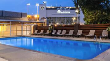 A swimming pool with lounge chairs and a building with 'VANDERBILT' signage in the background.