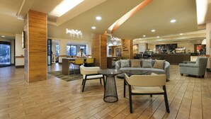 Een hotel lobby met een receptiebalie, een zithoek en een bar.