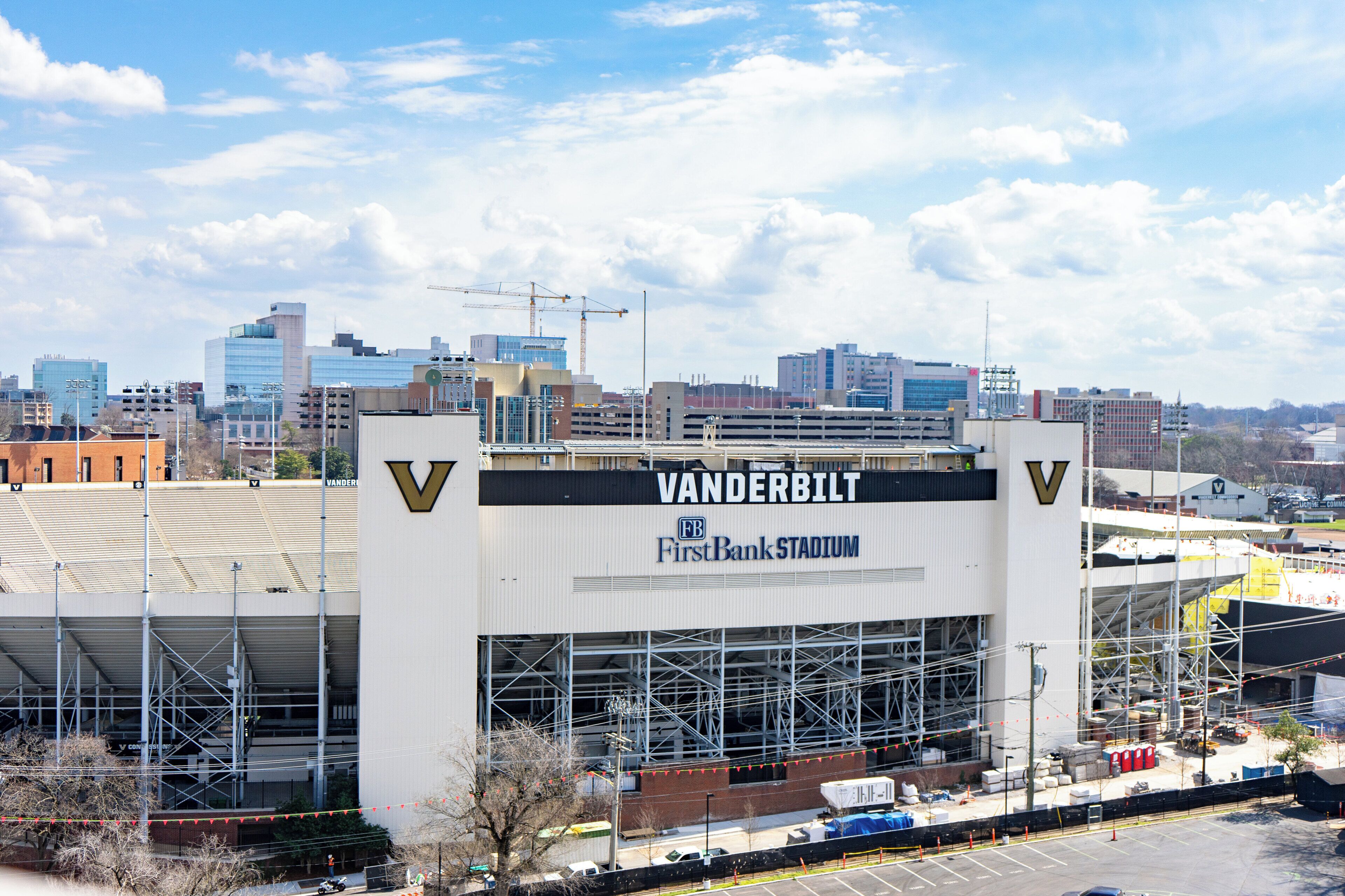 Un estadio grande con la señalización 'Vanderbilt FirstBank Stadium', rodeado de edificios urbanos y construcción.