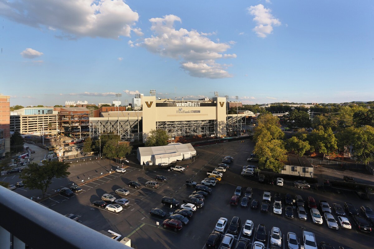 A parking lot with multiple cars, a large building with 'VANDERBILT' signage, and a clear sky.