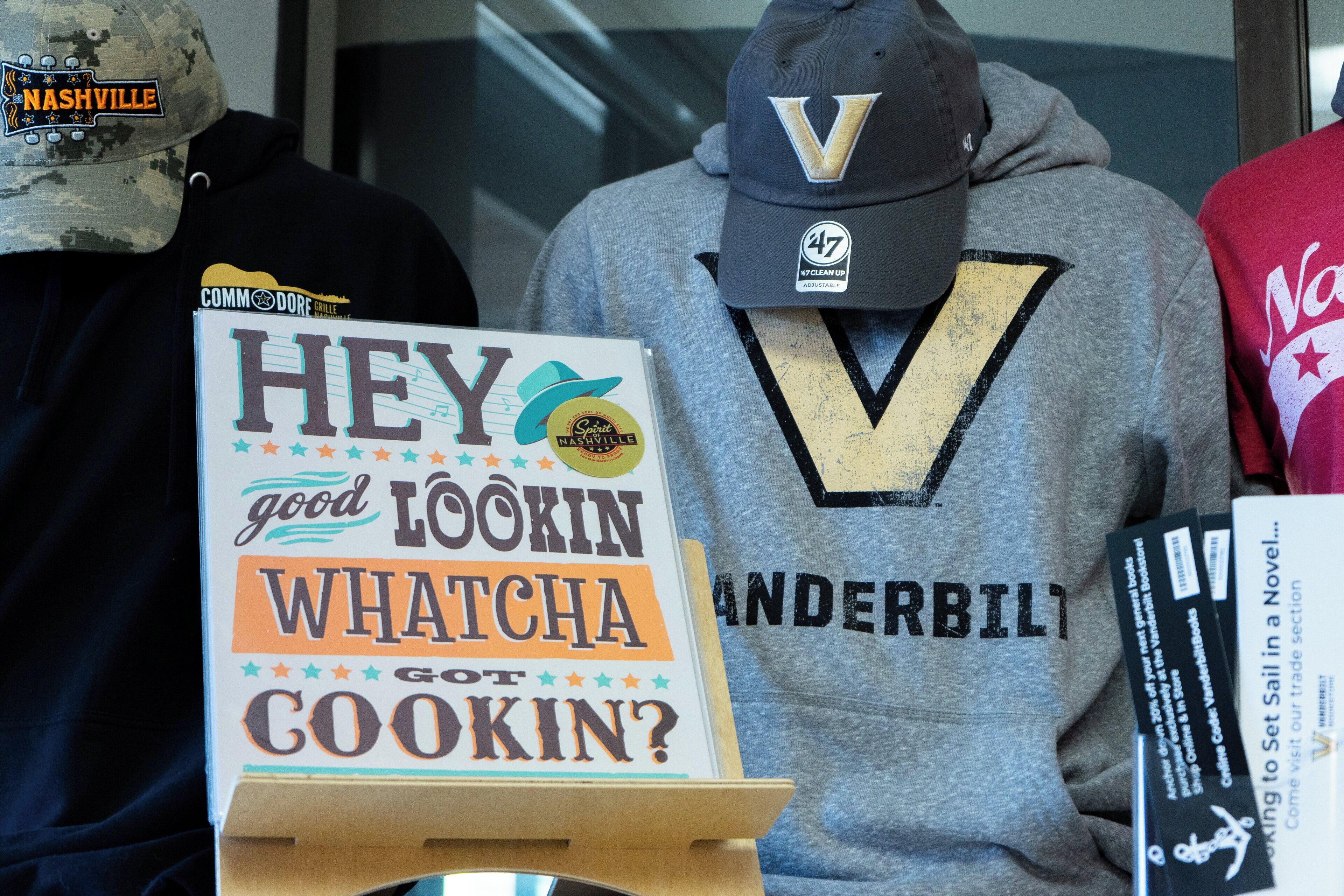 A display with a sign reading "HEY LOOKIN WHATCHA GOT COOKIN?" and a hoodie with "VANDERBILL" text.