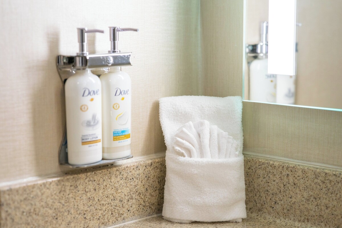 A bathroom with a towel rack holding a white towel and two Dove lotion bottles.