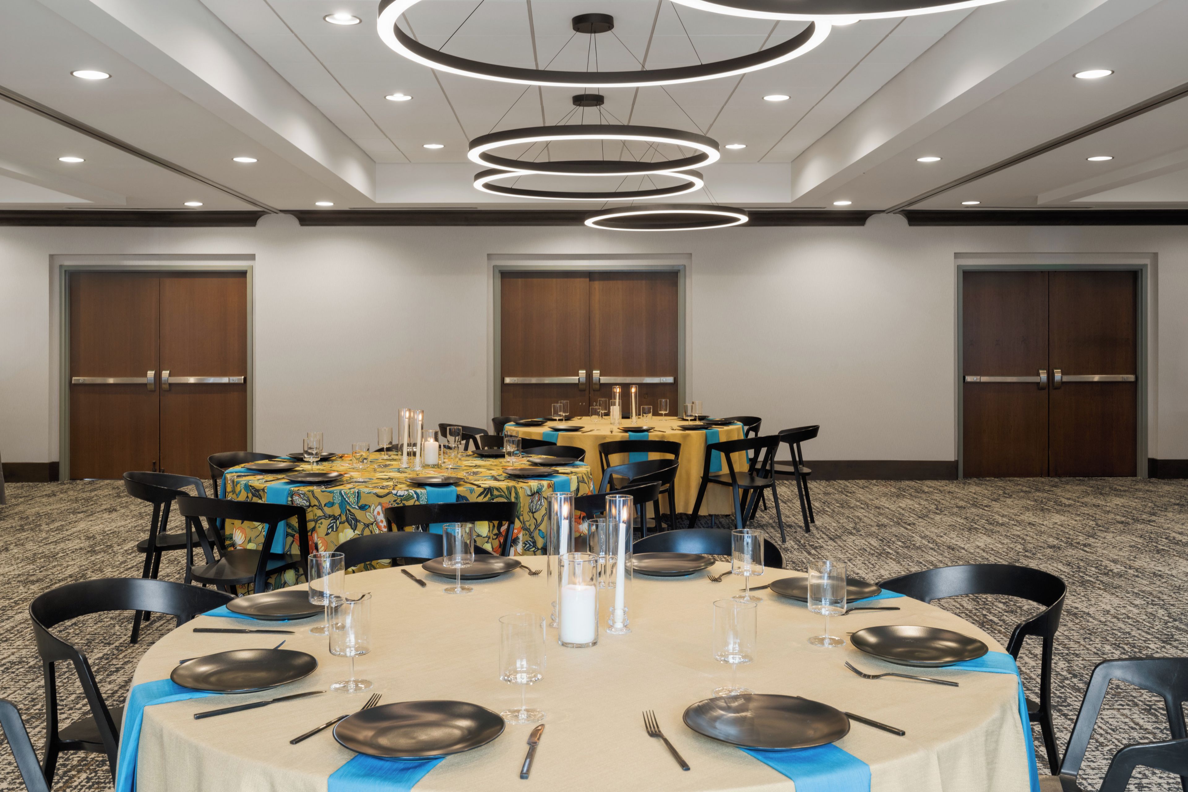 A conference room with a round table set for a meeting, equipped with chairs, plates, cutlery, and glasses.