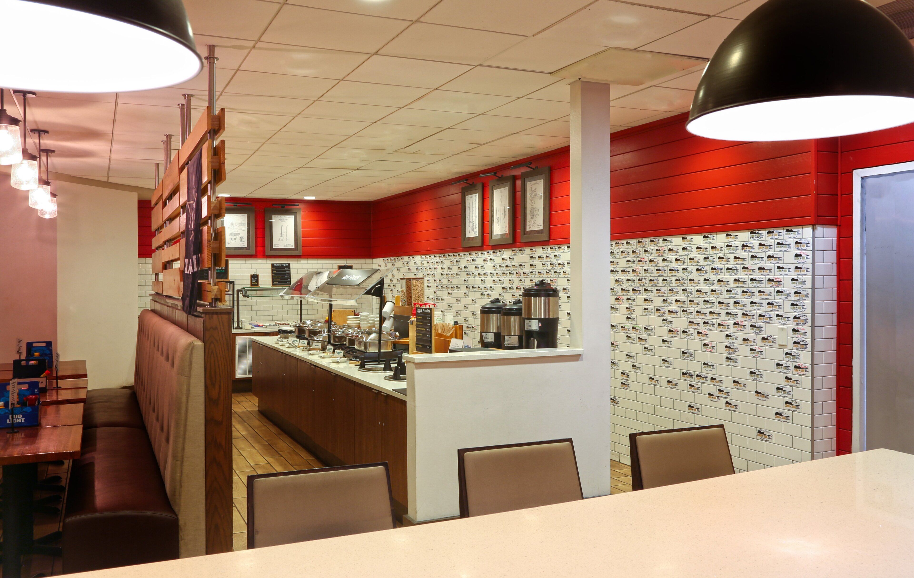 A restaurant with a counter, seating area, and a wall with numerous small windows.