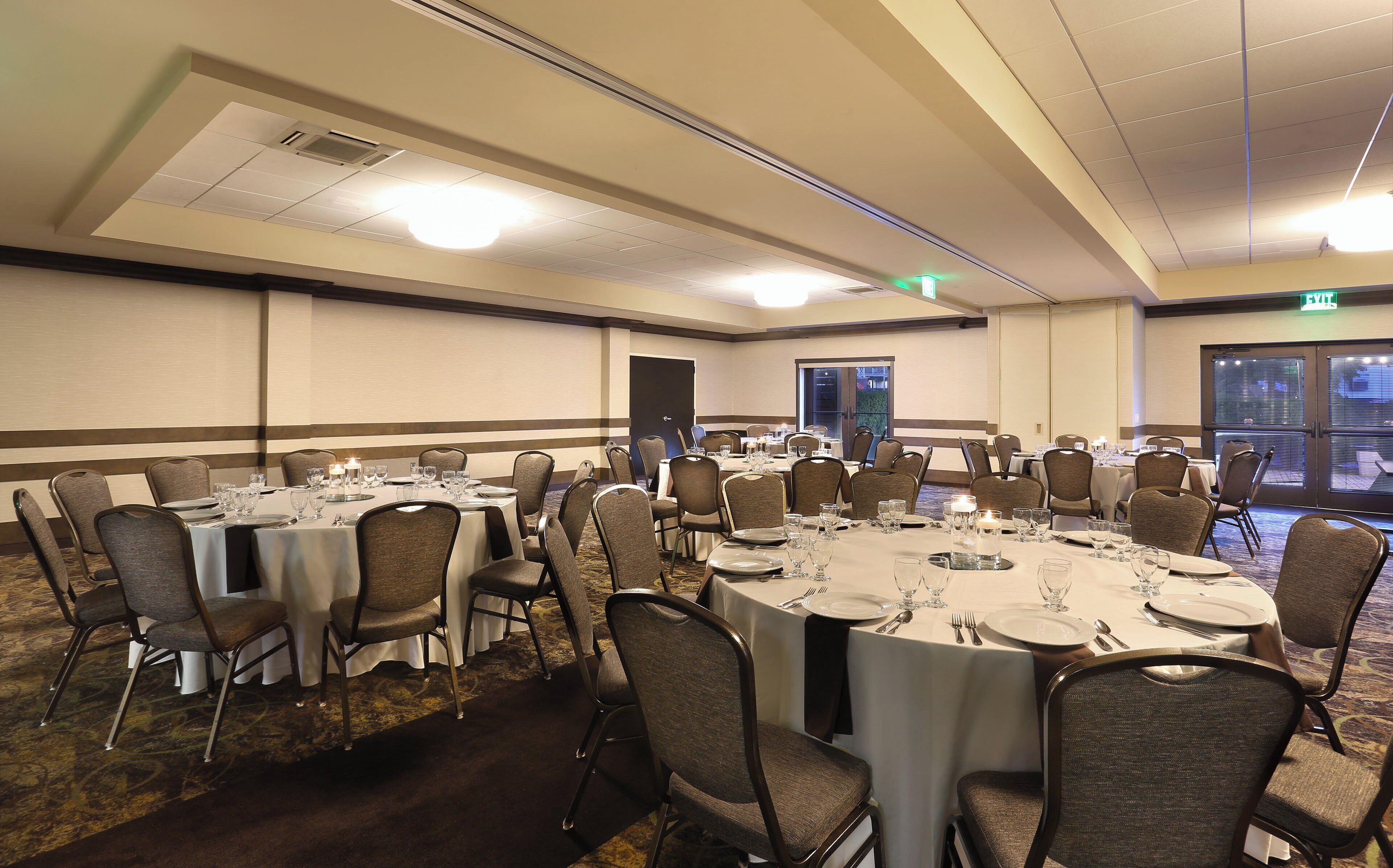 A conference room with round tables, chairs, and a carpeted floor.