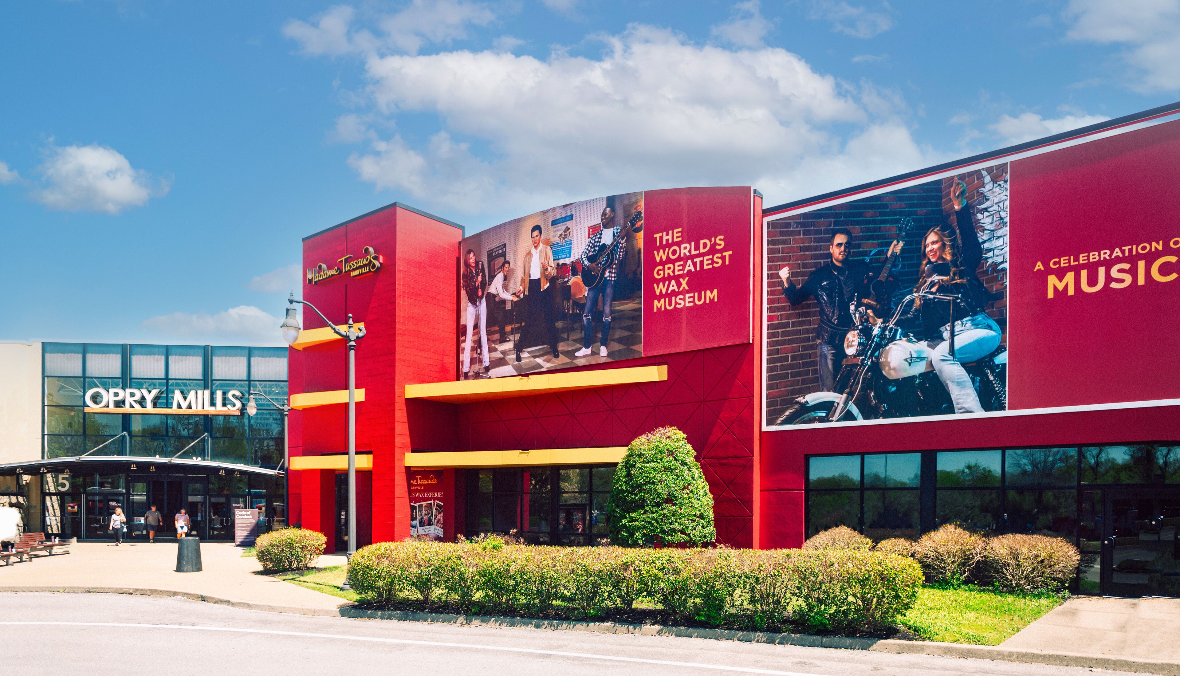 Un edificio con fachada roja, grandes carteles que anuncian 'The World's Greatest Wax Museum' y 'A Celebration of Music', y un cielo despejado.