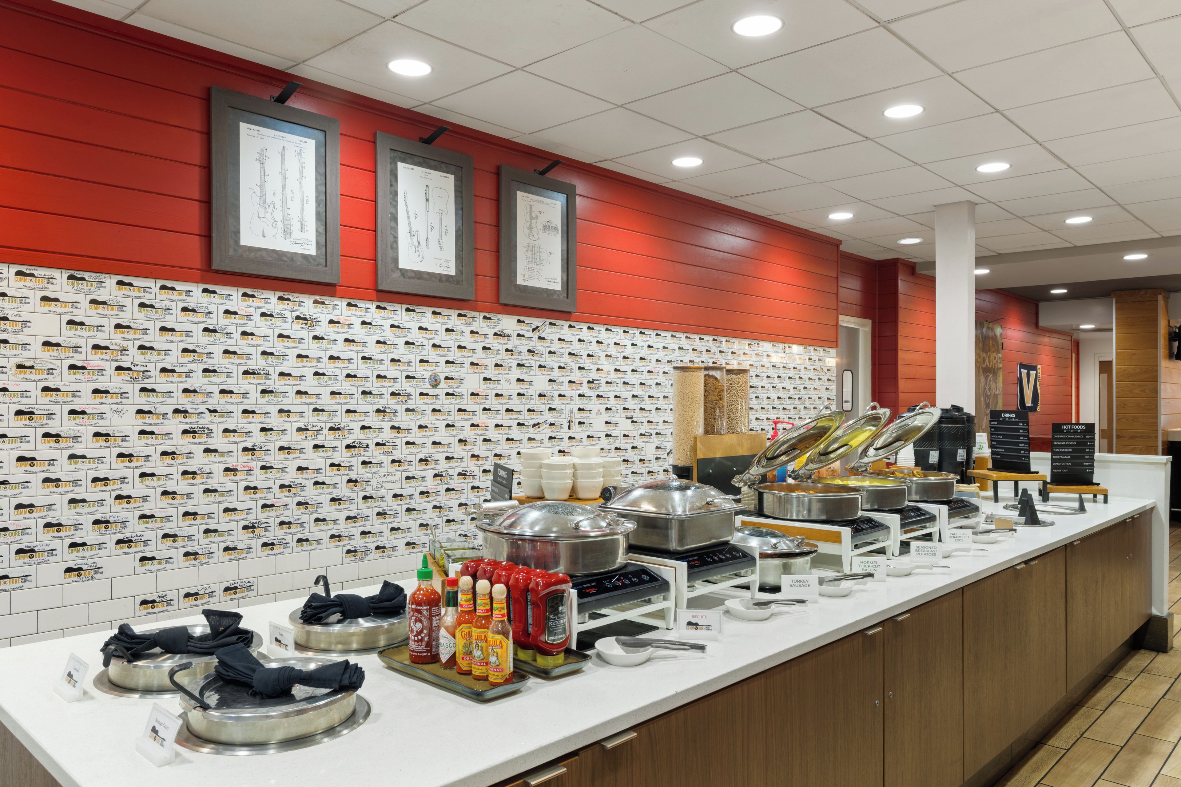 Un área de bufé con diversas estaciones de comida, que incluyen una estación de bebidas y una de alimentos calientes.