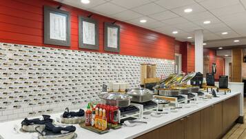 Un espace buffet proposant différents stands de nourriture, notamment un stand de boissons et un stand de plats chauds.
