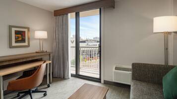 Habitación de hotel con escritorio, silla, sofá y vista al Estadio Vanderbilt.