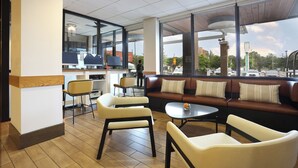 Een modern interieur met een zithoek, een balie met computers en grote ramen met uitzicht op de straat.