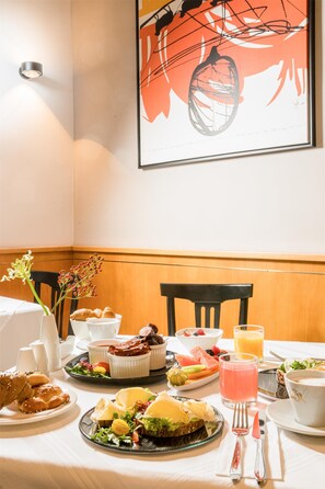 A dining table set with various dishes, including a salad, sandwiches, and fruit, along with cups and a glass of juice. - Best Western Hotel Moran (Prague)