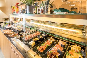 Un bufé con diversas opciones de comida, incluyendo carnes, quesos y postres.