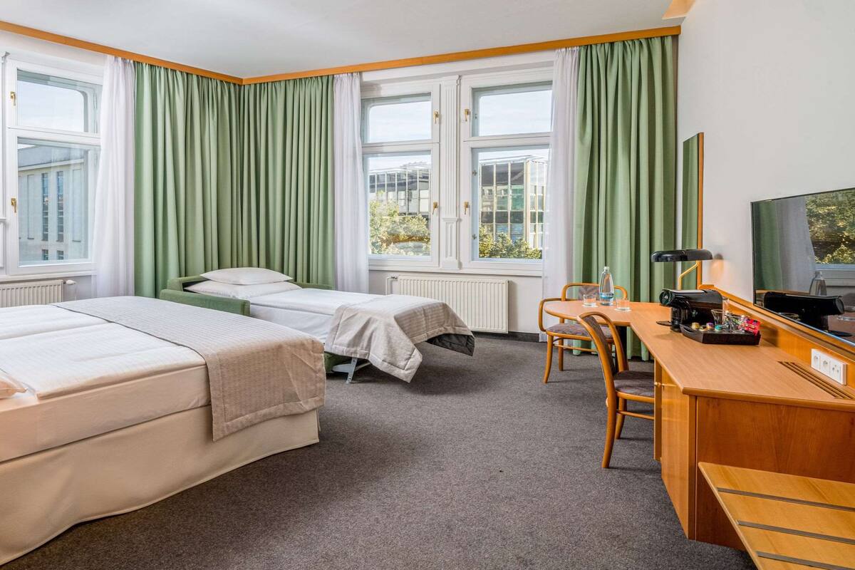 Een hotelkamer met twee bedden, een bureau met stoel, een telefoon en een televisie.