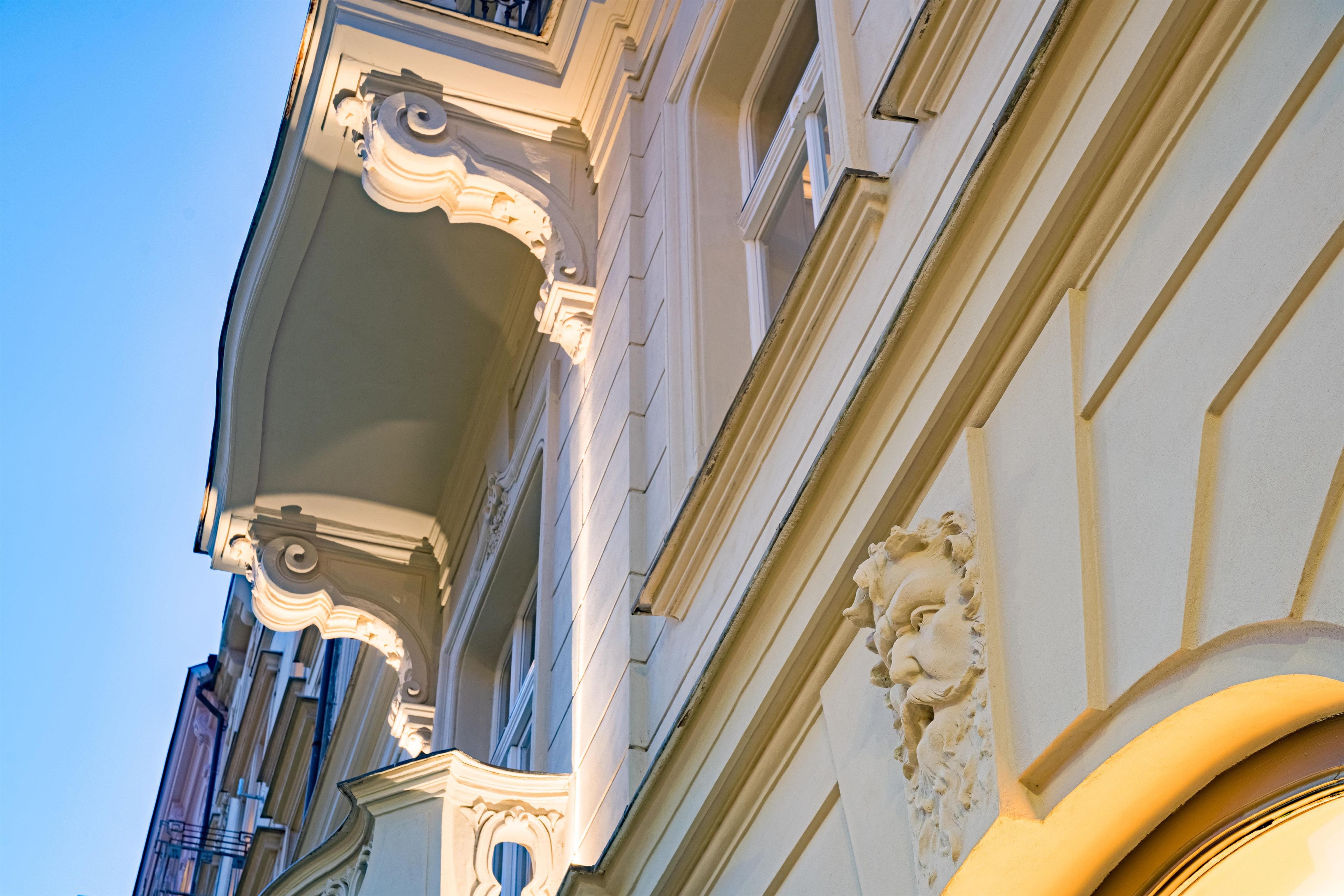 A building facade with ornate architectural details, including a decorative balcony and a sculptural element.