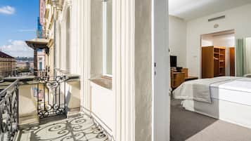 Une chambre d’hôtel avec un balcon, un lit, une armoire et une vue sur la ville.