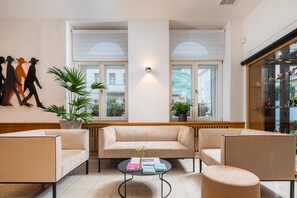 Un intérieur moderne avec un canapé, des fauteuils, une table basse et un mur orné de silhouettes découpées.
