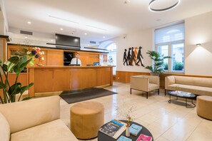 Un vestíbulo de hotel con mostrador de recepción, zona de estar y un amplio ventanal.