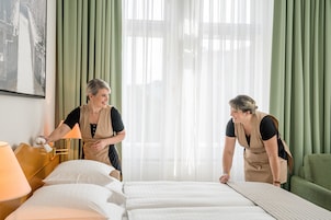 Una habitación de hotel con una cama, una mesita de noche con una lámpara y una cortina verde.