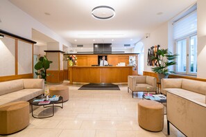 A hotel lobby with a reception desk, seating area, and a view of the kitchen. - Best Western Hotel Moran (Prague)