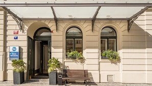 A hotel entrance with a sign for 'Best Western City Hotel Moran,' a bench, and potted plants. - Best Western Hotel Moran (Prague)