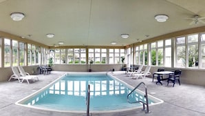 Ein Hallenbad mit freiem Blick auf die grüne Landschaft durch große Fenster.