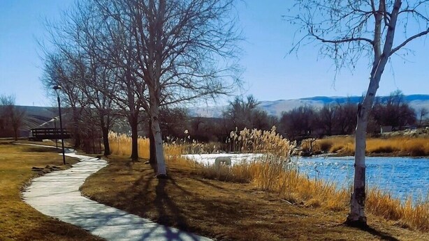 A paved pathway, leafless trees, and a body of water in a park setting. - Hot Springs Hotel and Spa (Thermopolis)