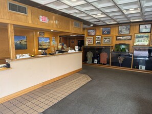 A reception desk with a 'WELCOME' sign, a 'EXIT' sign, and framed pictures on the walls.