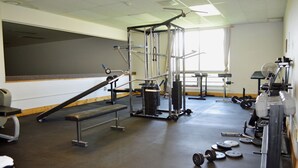 A gym with various exercise equipment, including a bench, weight racks, and a squat rack. - Hot Springs Hotel and Spa (Thermopolis)