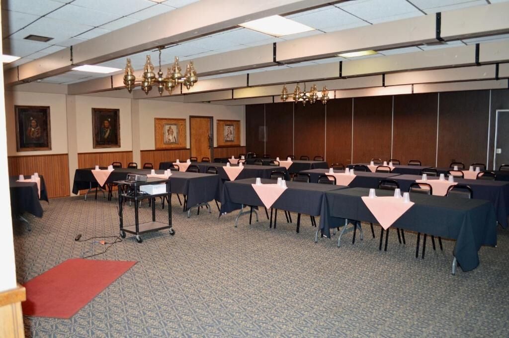 A conference room with multiple tables, chairs, and a podium.